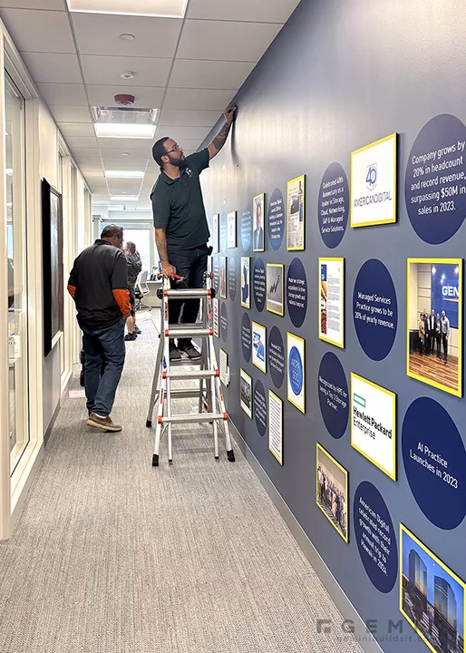 Gemini Builds It installers mounting printed vinyl circles and framed panels onto the American Digital history wall