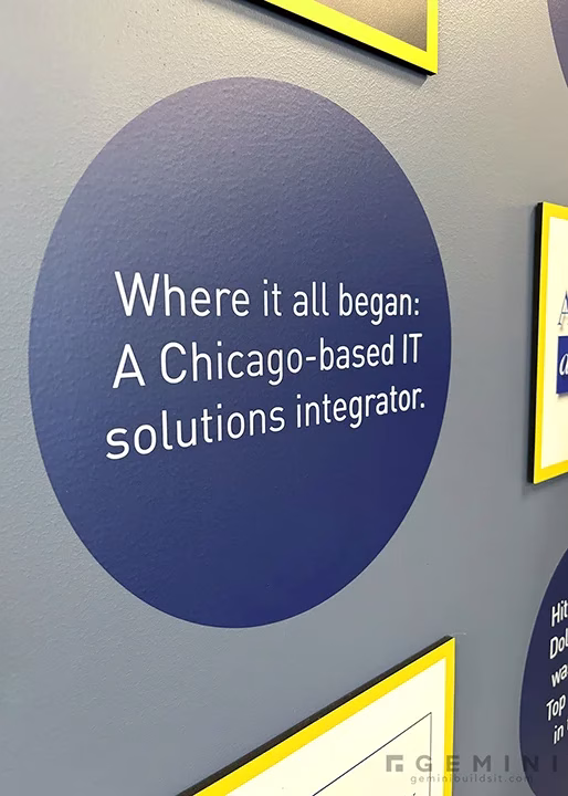 Printed vinyl circle on corporate history wall reading Where it all began, a Chicago-based IT solutions integrator